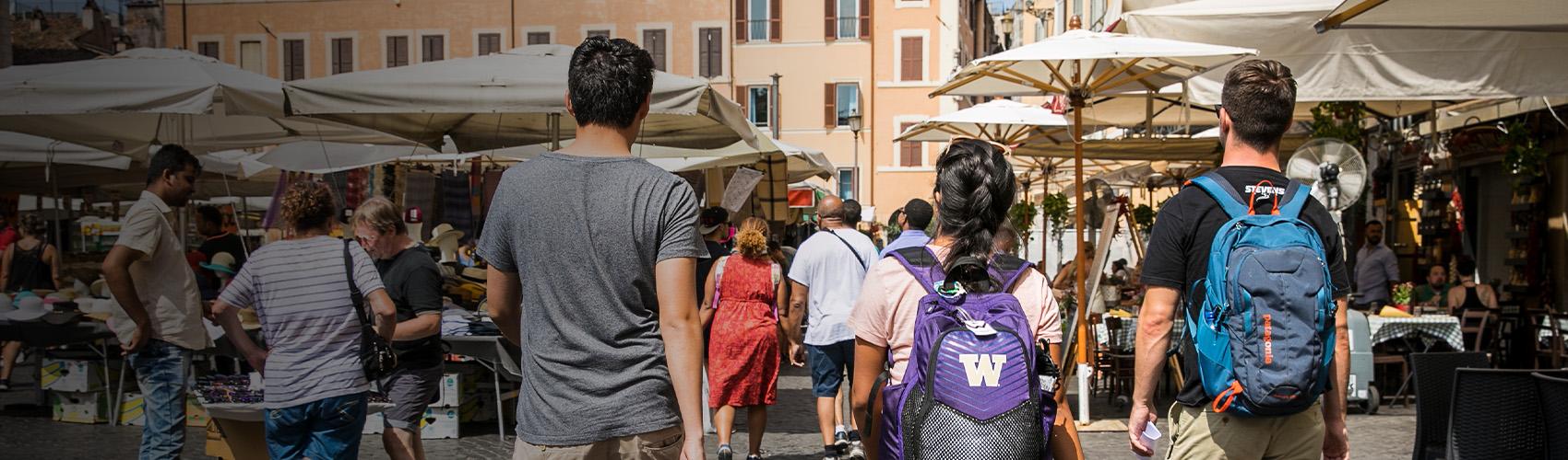 Group of students, one wearing a UW backpack, in a bustling foreign market